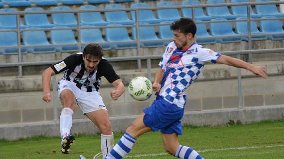 Joselu, delanetro del Badajoz, centra presionado por Álex, defensor del Arroyo