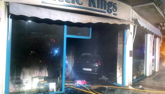 Un coche choca contra una tienda y arde en Cáceres
