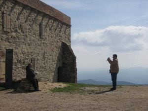 RETRATO PARA EL RECUERDO. Una pareja de turistas se fotografía a un paso de la puerta de entrada del sólido monasterio extremeño de Tentudía. / ESPERANZA RUBIO.