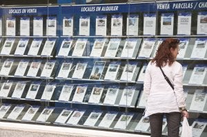Una mujer consulta el escaparate de una agencia inmobiliaria de Badajoz. ::                             PAKOPÍ