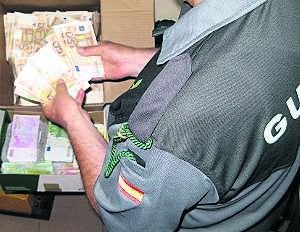 Un agente de la Guardia Civil con el dinero intervenido el jueves en Caya. ::                             HOY