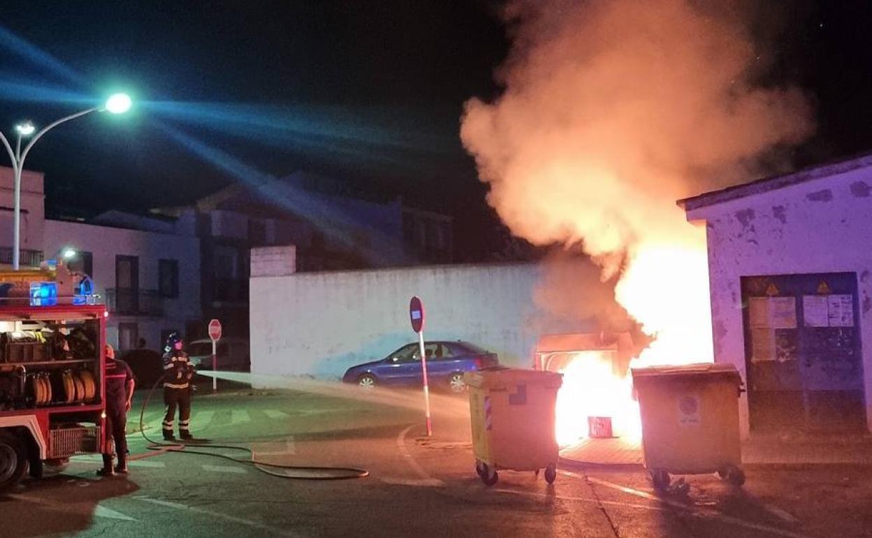 Los bomberos apagando uno de los contenedores 