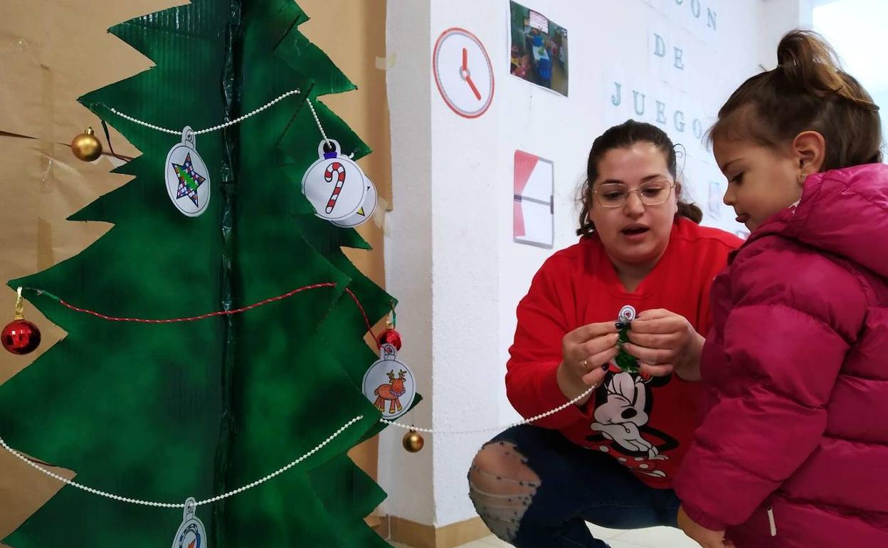 Una de las participates junto a una monitora colgando sus deseos 