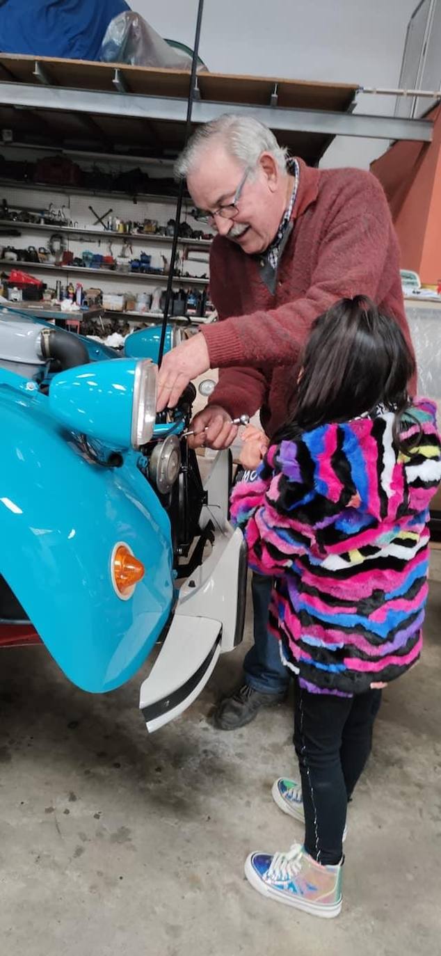 Pepín Álvarez junto a una de sus nietas arreglando un coche clásico 