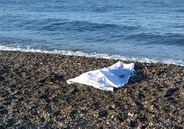Una de las víctimas de Adra, cubierta con una sábana en la orilla del mar.