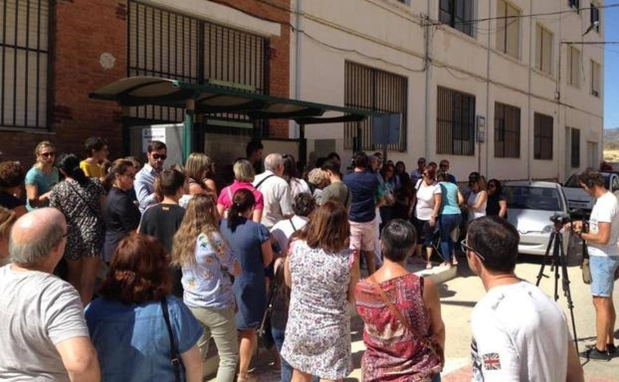 Concentración de padres en una parada de bus escolar.