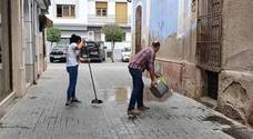 Dos comerciantes limpiando la calle en la mañana de ayer lunes. 