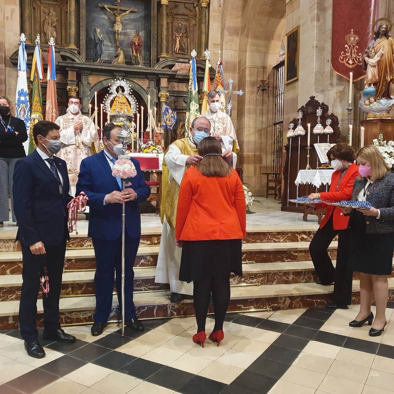 El arcipreste de la ciudad, Pedro Montesinos, impne la medalla a una nueva cofrade, entre los representantes de la Matriz, los diácconos permanentes, las banderasm cetros y una imagen de la Virgen vestida al estilo rococó de la época de 1.700. 