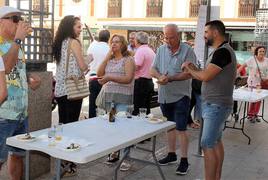 Vecinos degustan las sardinas aderezadas con bebidas en el exterior de la Plaza de Abastos.