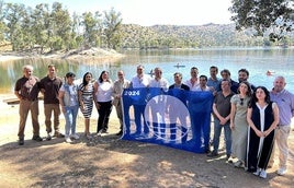 Los responsables de los organismos implicados posan con la bandera con el embalse de fondo.