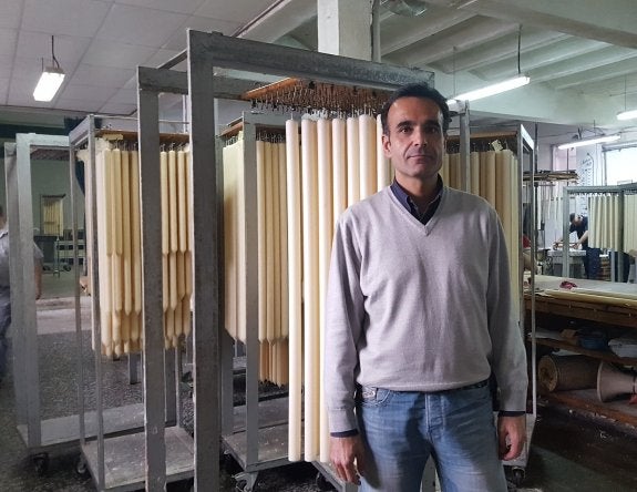 Manuel Bellido posa en su taller delante de un conjunto de velas en proceso de fabricación .