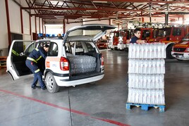 Bomberos cargando de botellas de agua para su reparto