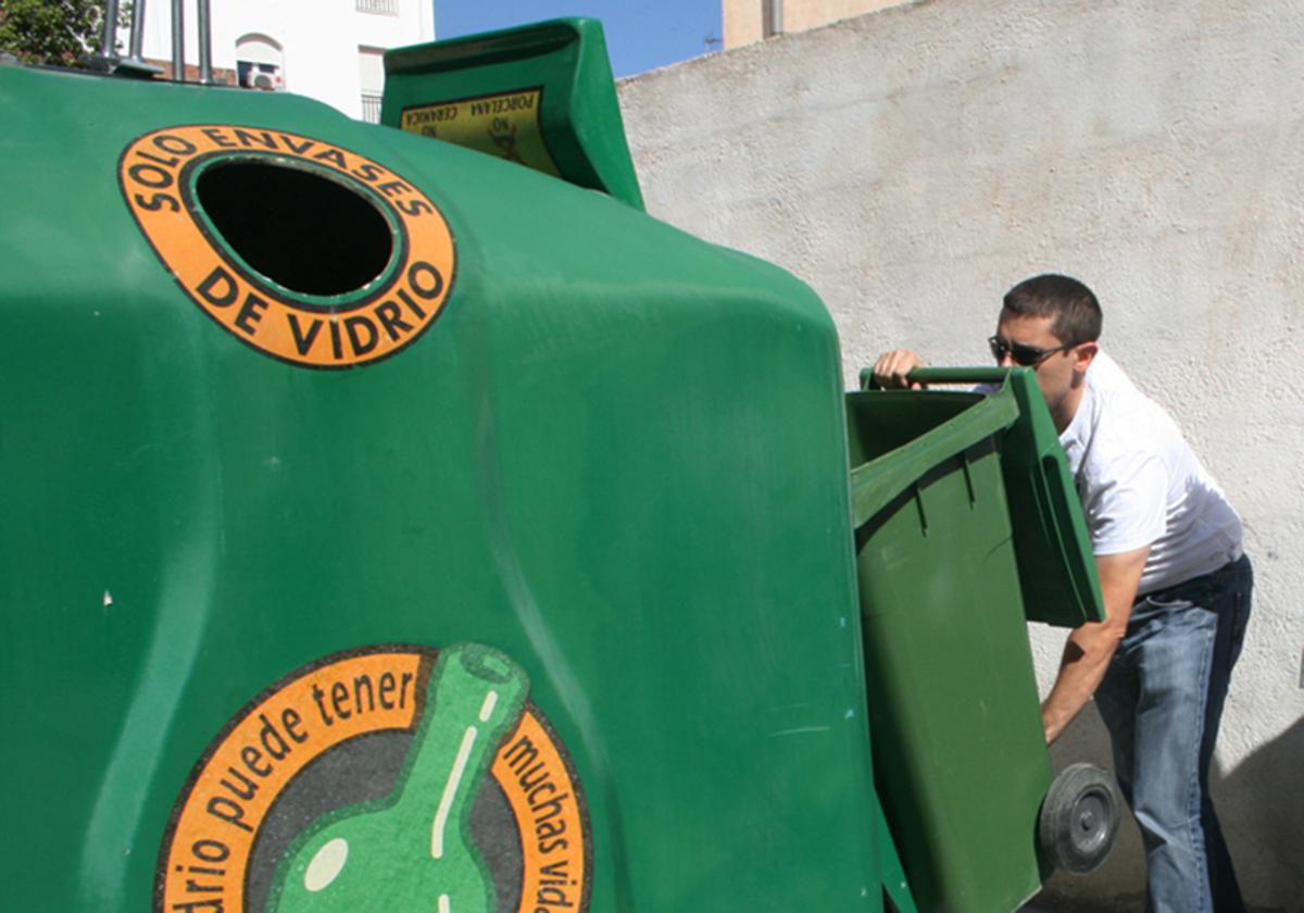 Depositando botellas de vidrio en un contenedor verde