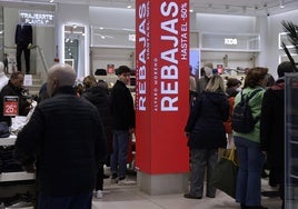 Clientes miran ropa en un establecimiento comercial.