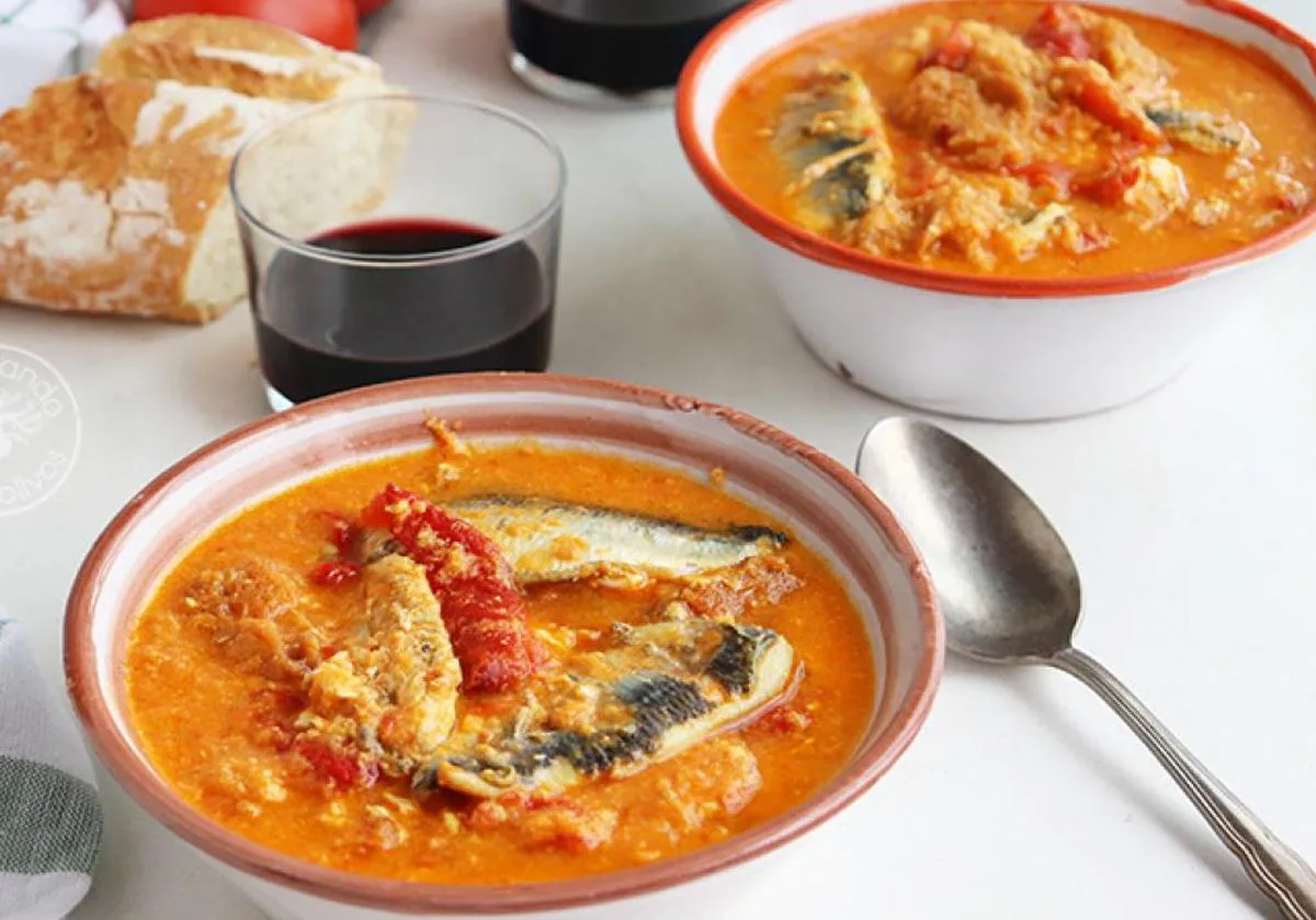 Presentación del plato de sopa de tomates y pimientos servida con lomos de sardina