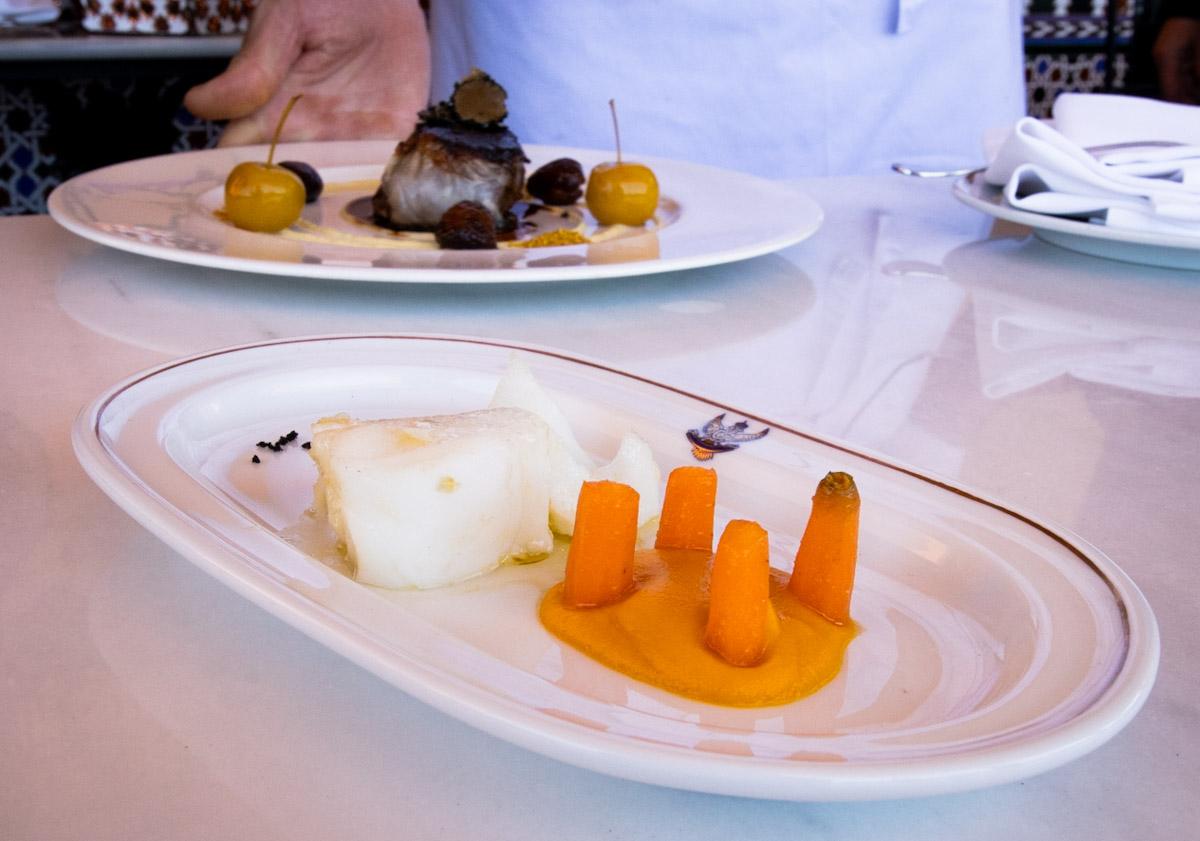 Imagen principal - El lomo de bacalao confitado y emulsión de zanahoria | El lomo de ciervo marinado en oloroso y trufa, chalota, manzana y castañas | Esaú Hita y César García, en la terraza del Palace. 