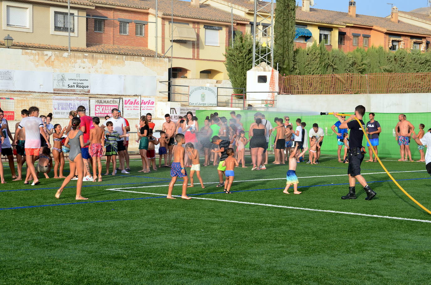 Un voluntario de Protección Civil de Huétor Vega da juego refrescando con una manguera.