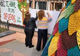 La alcaldesa y la concejala de Fiestas escriben deseos junto al árbol, en el Parque de la Encina.