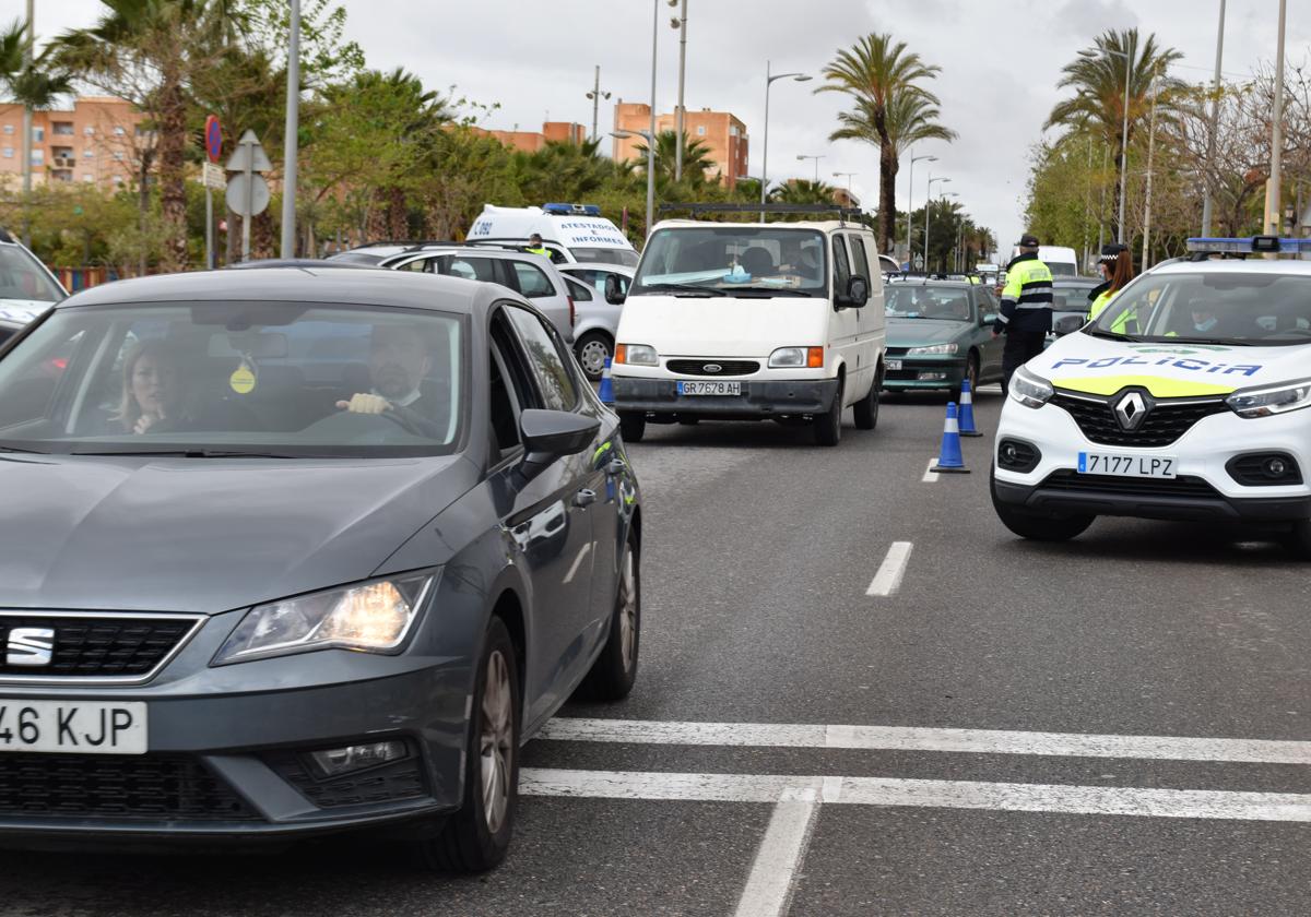 Varios vehículos pasan por una carretera de Vícar, bajo la atenta mirada de agentes de la Policía Local.