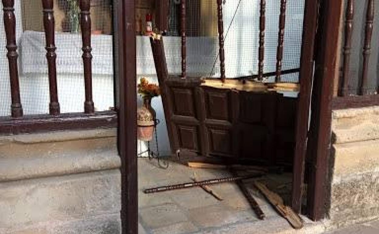 La verja y puerta de madera de la capilla tras sufrir los daños.