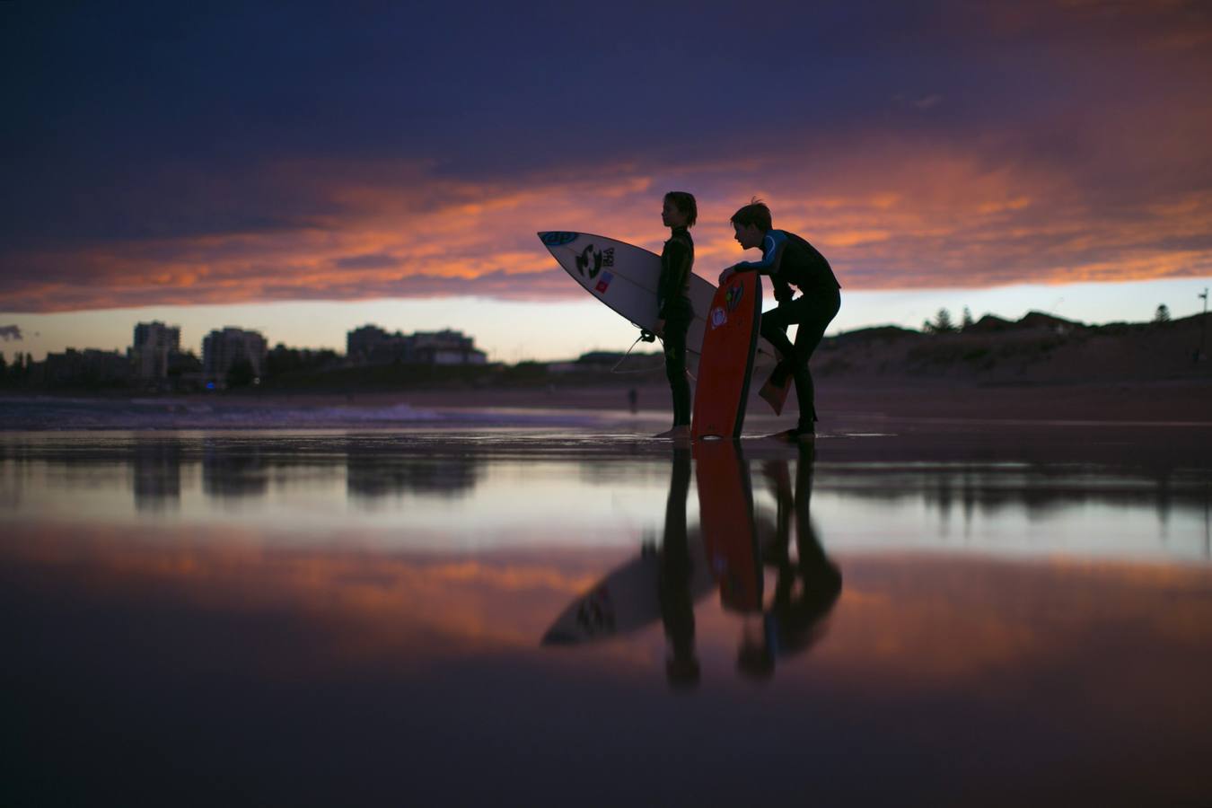 Jóvenes surfistas, apodados 'arandelas' en la jerga local de surf, esperan a sus amigos para terminar una sesión posterior a la puesta de sol sobre las olas de Wanda Beach en Sydney.
