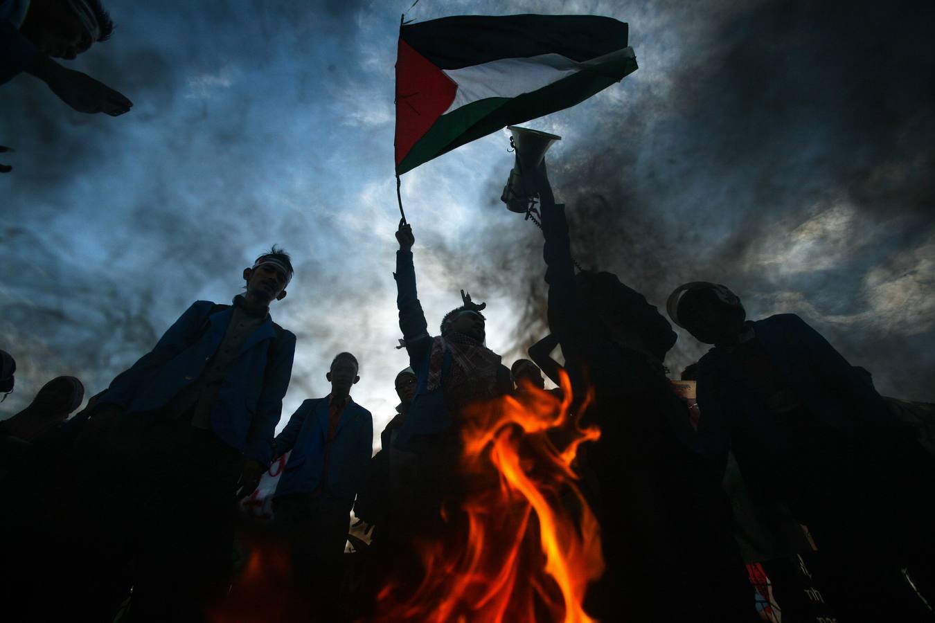 Manifestantes indonesios izar la bandera palestina, mientras se queman una bandera israelí y EE.UU. durante una manifestación en Banda Aceh, en la isla de Sumatra.