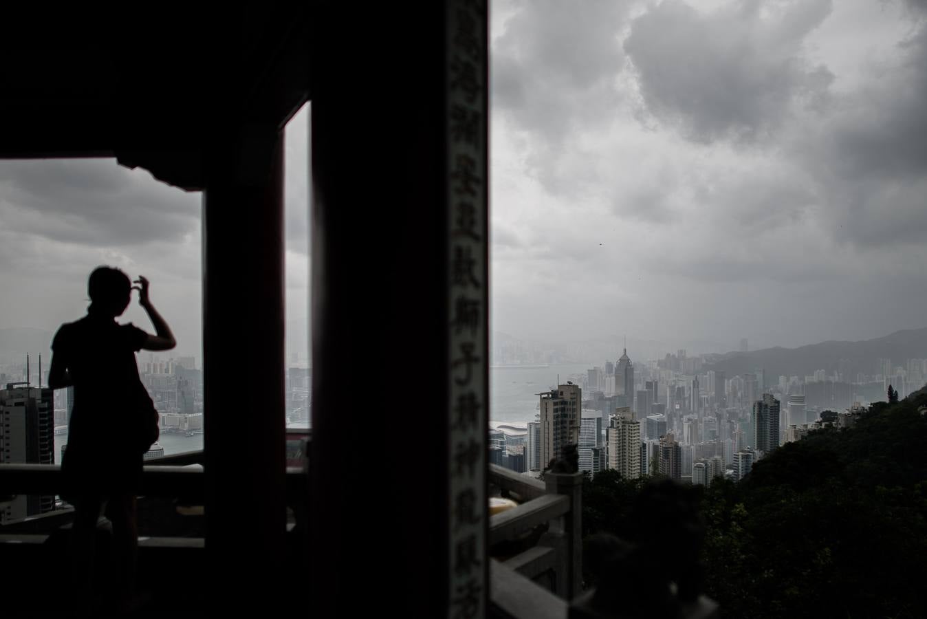 Una mujer mira el horizonte de Hong Kong, mientras que las tormentas se acumulan.
