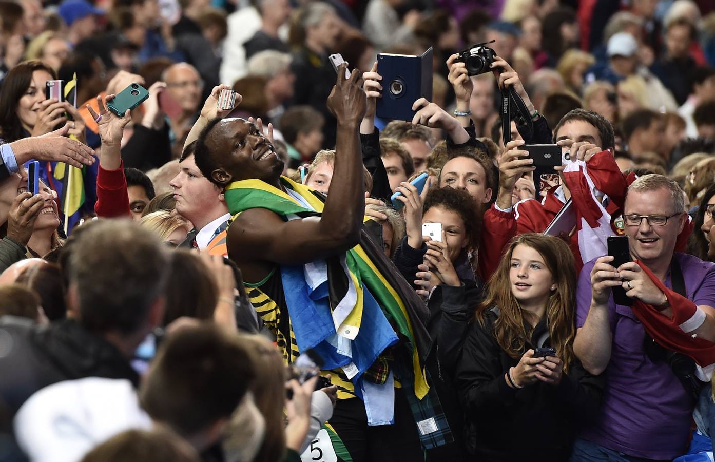 Usain Bolt posa para los aficionados después de ganar la final del 4 x 100 metros relevos de atletismo en el estadio Hampden Park.