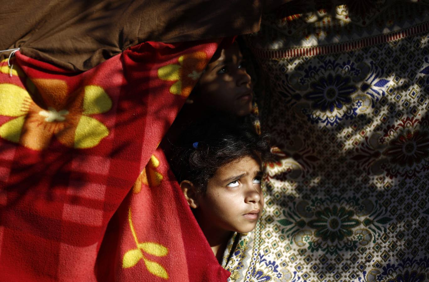 Un niño palestino desplazado mira hacia cielo en busca de aviones en Beit Lahia en el norte de la Franja de Gaza.