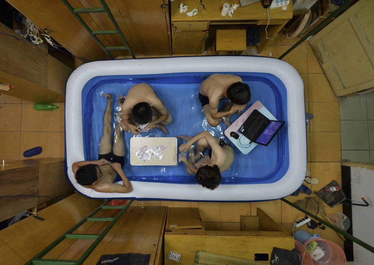 Los estudiantes universitarios se refrescan en el interior de una piscina inflable durante el calor del verano, en su dormitorio en Wuhan, provincia de Hubei.