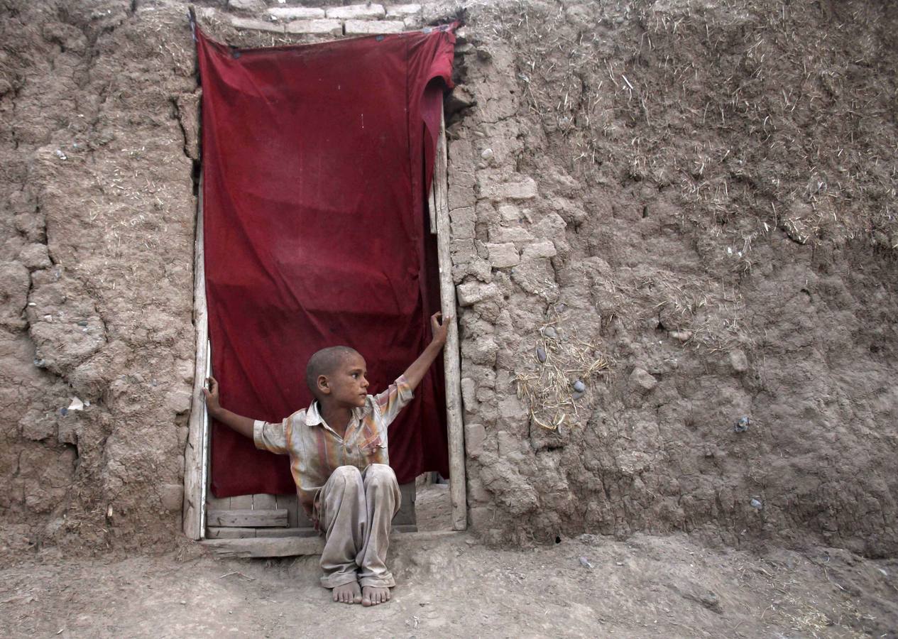 Un niño refugiado afgano se sienta a la puerta de su casa en la aldea de las afueras de Peshawar Sardaryab.