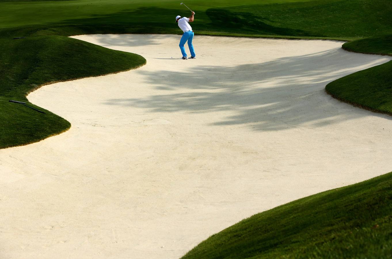 Rory McIlroy de Irlanda del Norte realiza un disparo desde un búnker durante una ronda de práctica.