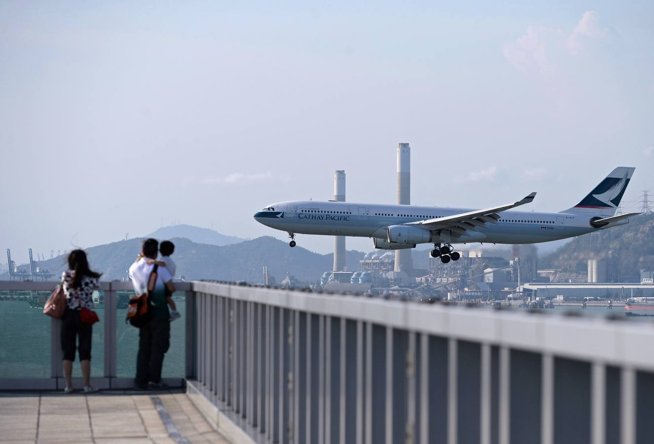 La gente ve como un avión de pasajeros se prepara para aterrizar en el aeropuerto internacional de Hong Kong.