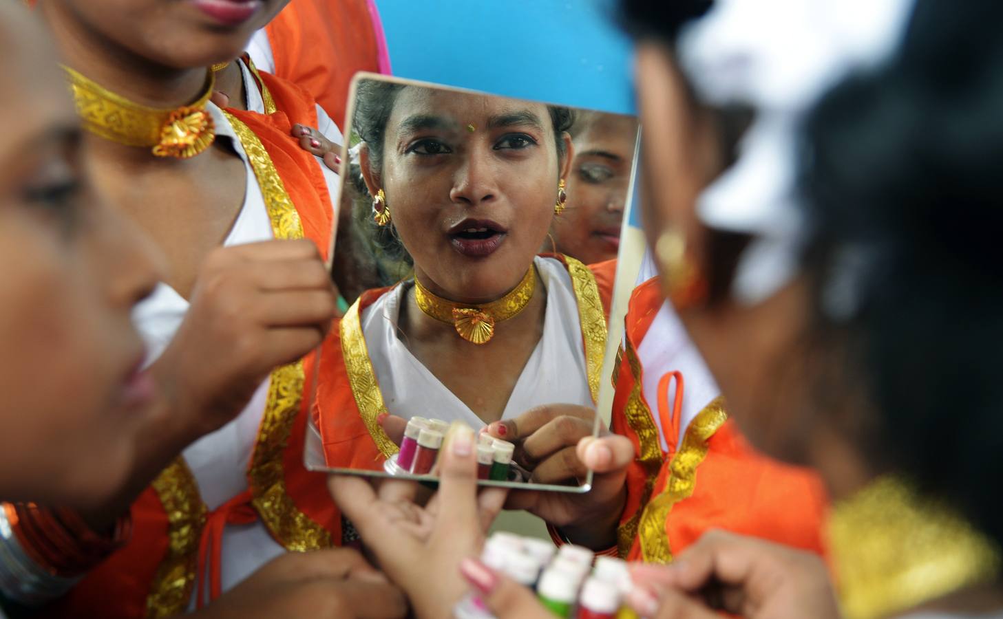 Un estudiante de la India se refleja en un espejo mientras se aplica los toques finales.