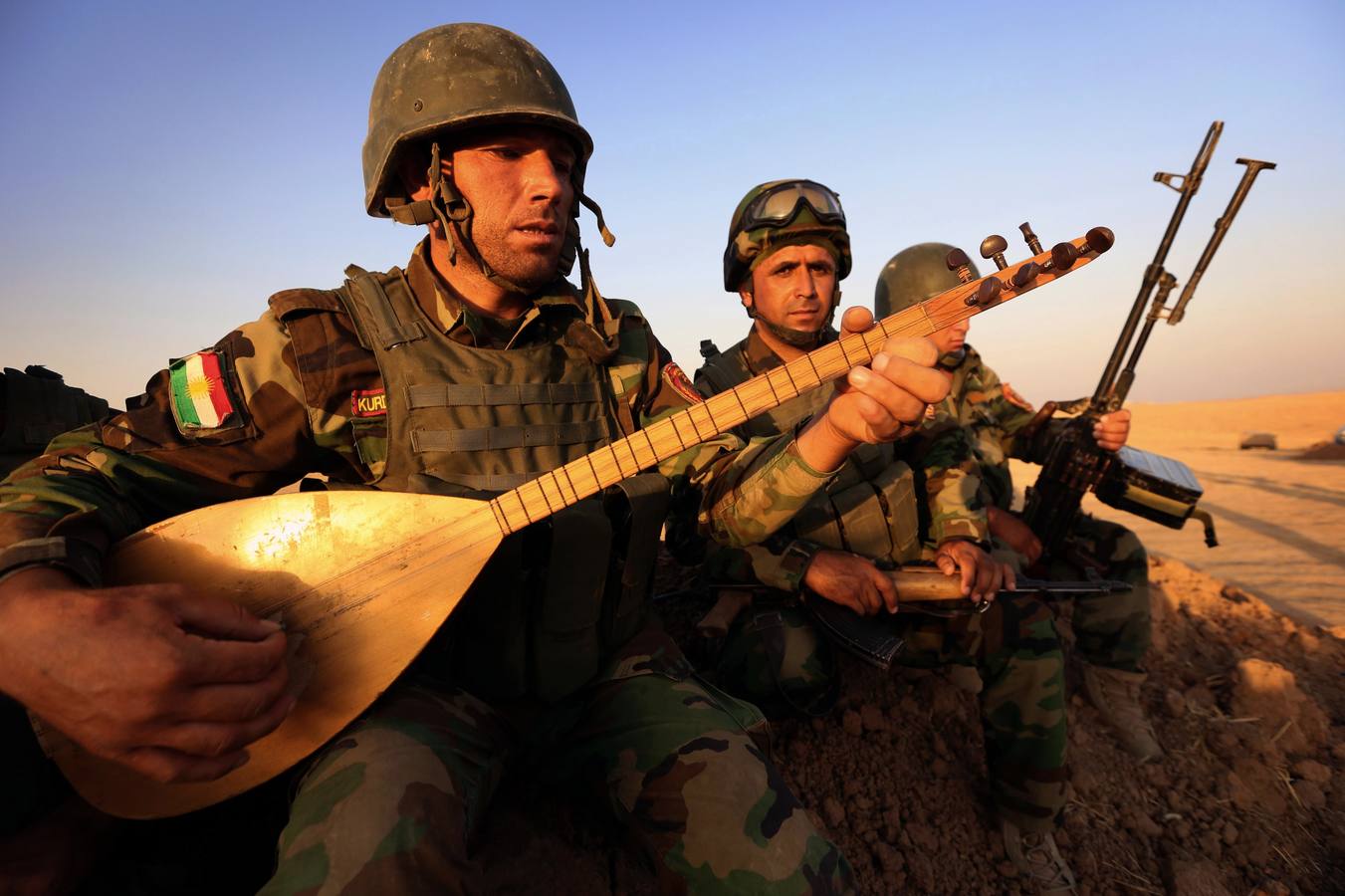 Un combatiente kurdo toca un instrumento musical en la línea de frente en Khazer.