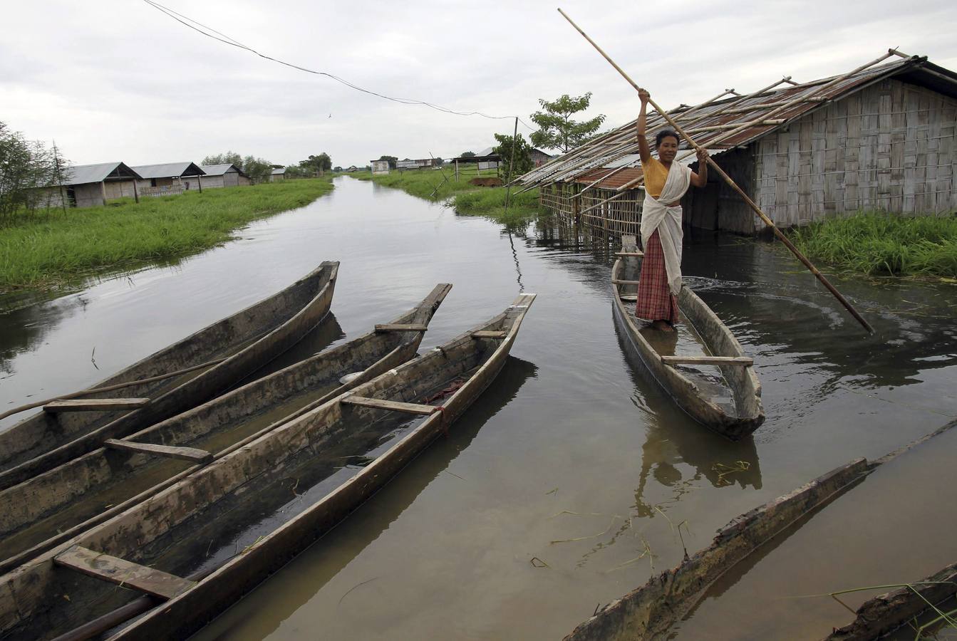 Una mujer utiliza un bote para trasladarse a una zona más segura en el estado indio nororiental de Assam.