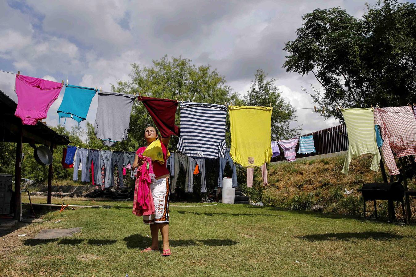 Crystal Ibarra, cuelga su ropa en su patio trasero, que da a la valla fronteriza en la frontera México-Estados Unidos fuera de Brownsville, Texas.