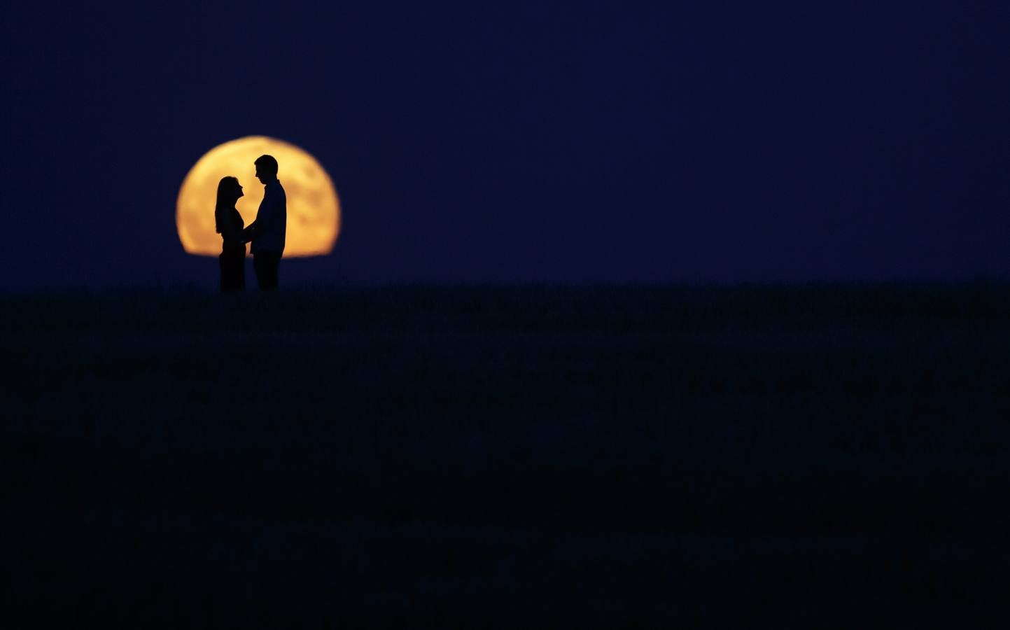 Una pareja de pie delante de la luna llena en Burgos.