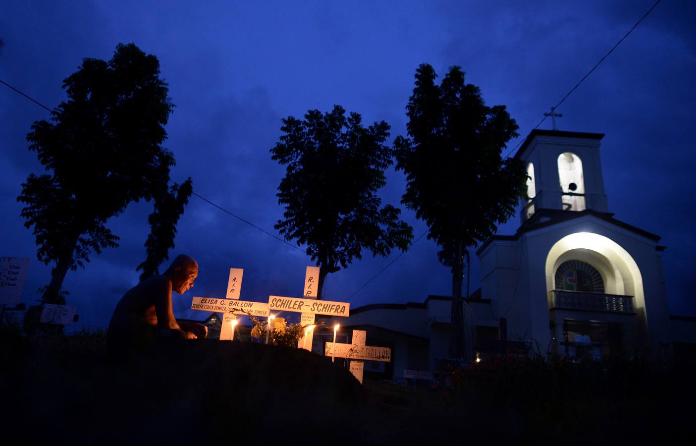 Un familiar de una víctima de Tyhpoon Haiyan visita un cementerio frente a la Iglesia de San Joaquín en Palo.