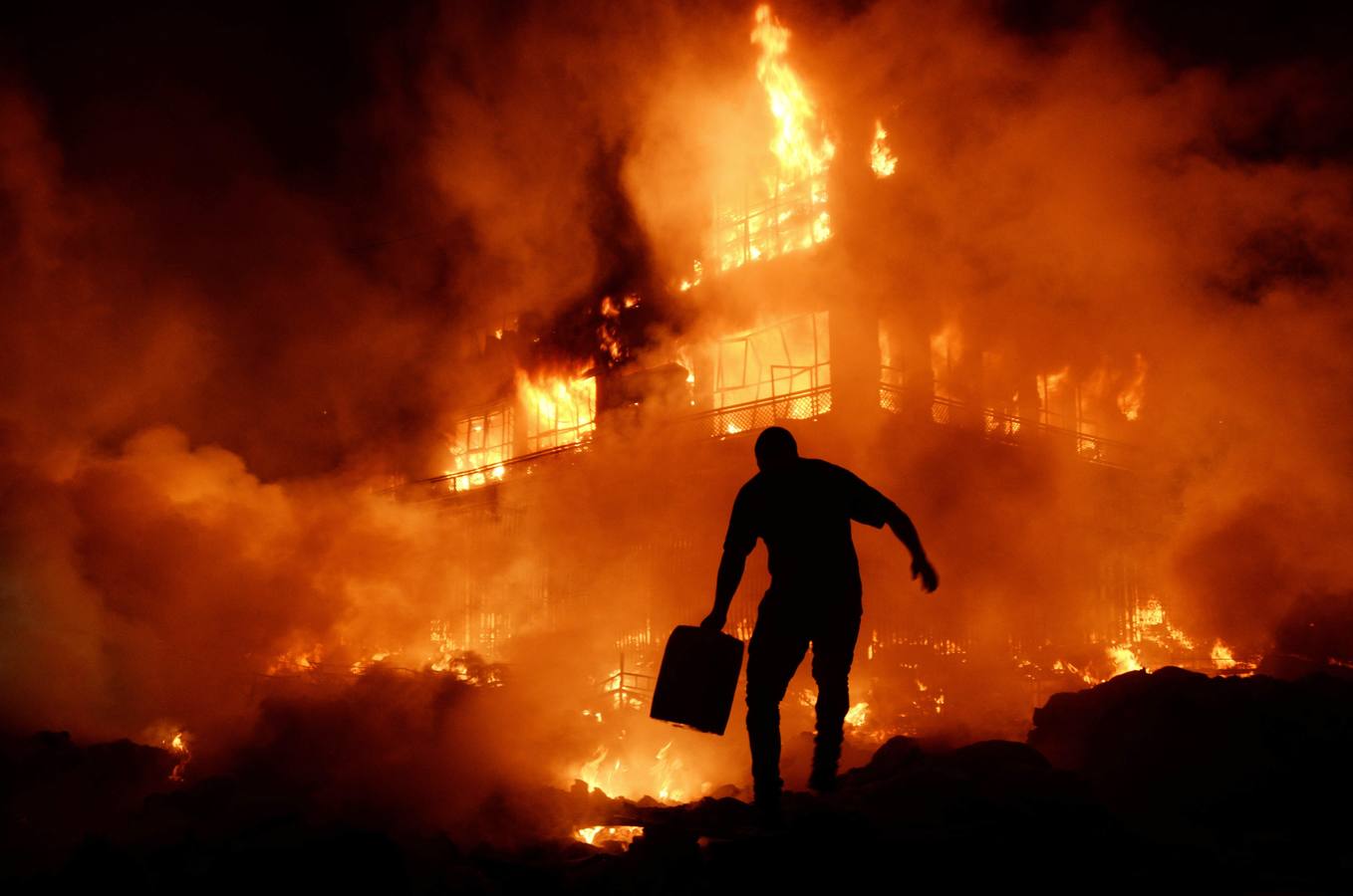 Un afgano lleva un recipiente de agua en su intento de apagar un voraz incendio en el mercado central de Mazar-i-Sharif.