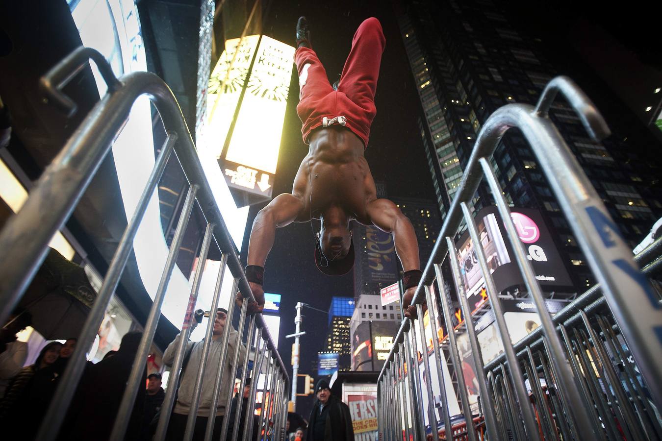 Un hombre que se identificó como Wildcat hace ejercicio en las barricadas de control de masas NYPD bajo la lluvia en Times Square en Nueva York. Wildcat dice que trabaja en lugares públicos para animar a otros a mejorar su salud sin necesidad de equipo de lujo .