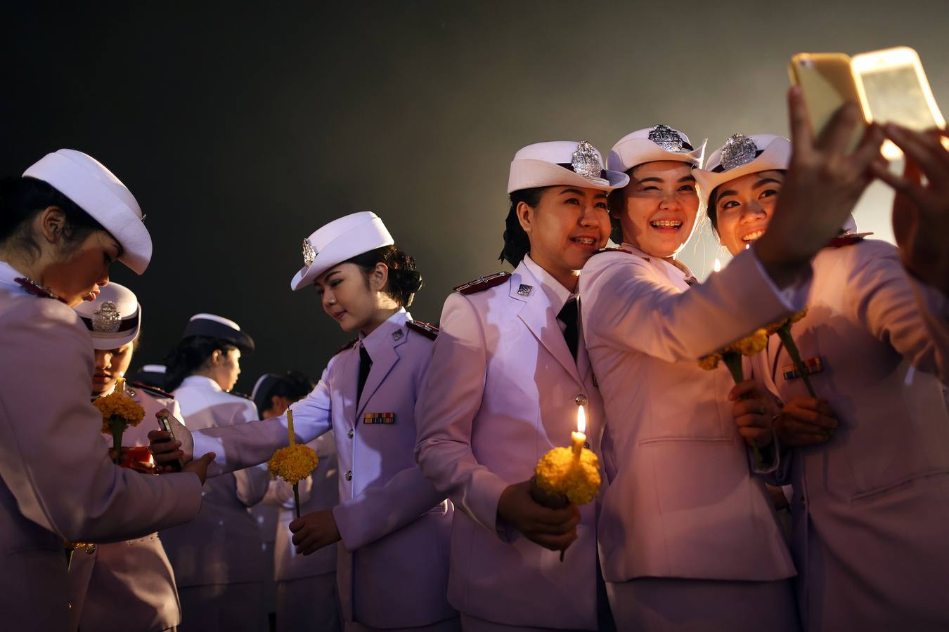 Cadetes militares toman fotos de sí mismos durante una ceremonia para celebrar el cumpleaños del rey de Tailandia.