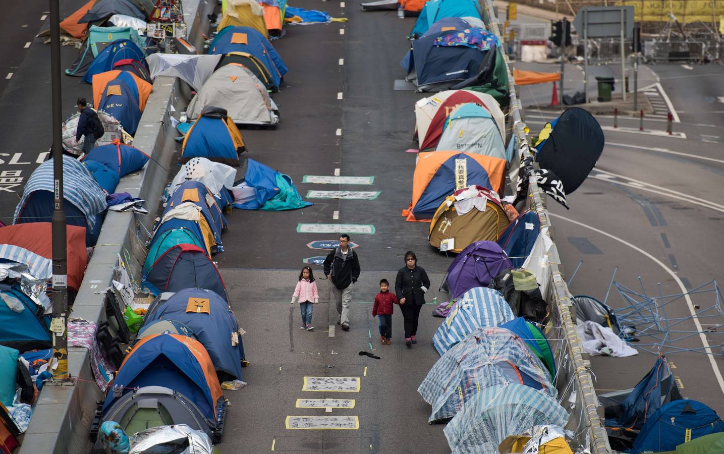 Una familia camina entre las tiendas de campaña en el lugar de la protesta del movimiento en el distrito Almirantazgo de Hong Kong.