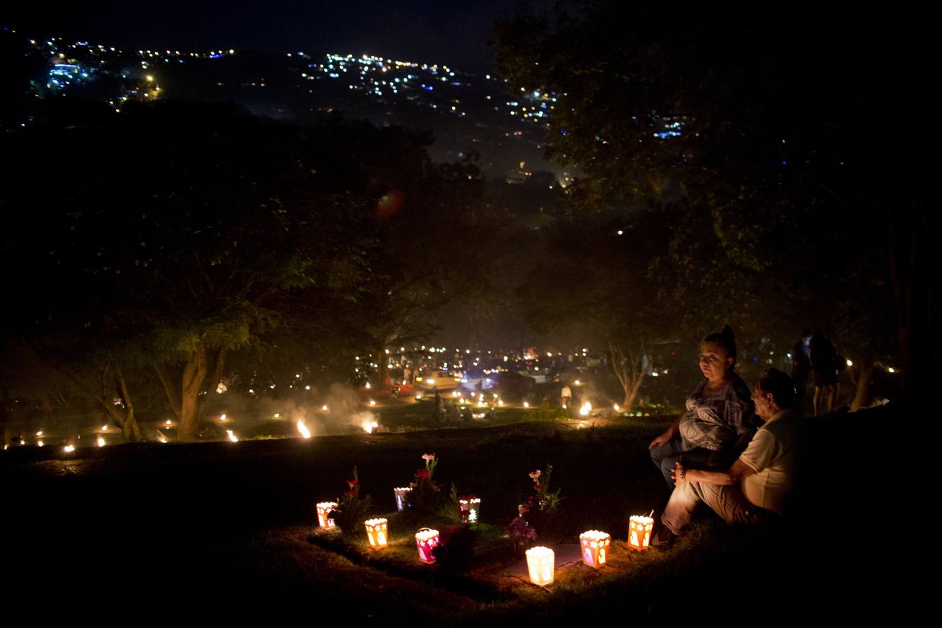 Personas velan ante la tumba de un familiar durante las celebraciones por el Día de las Velitas en Cali, Colombia.