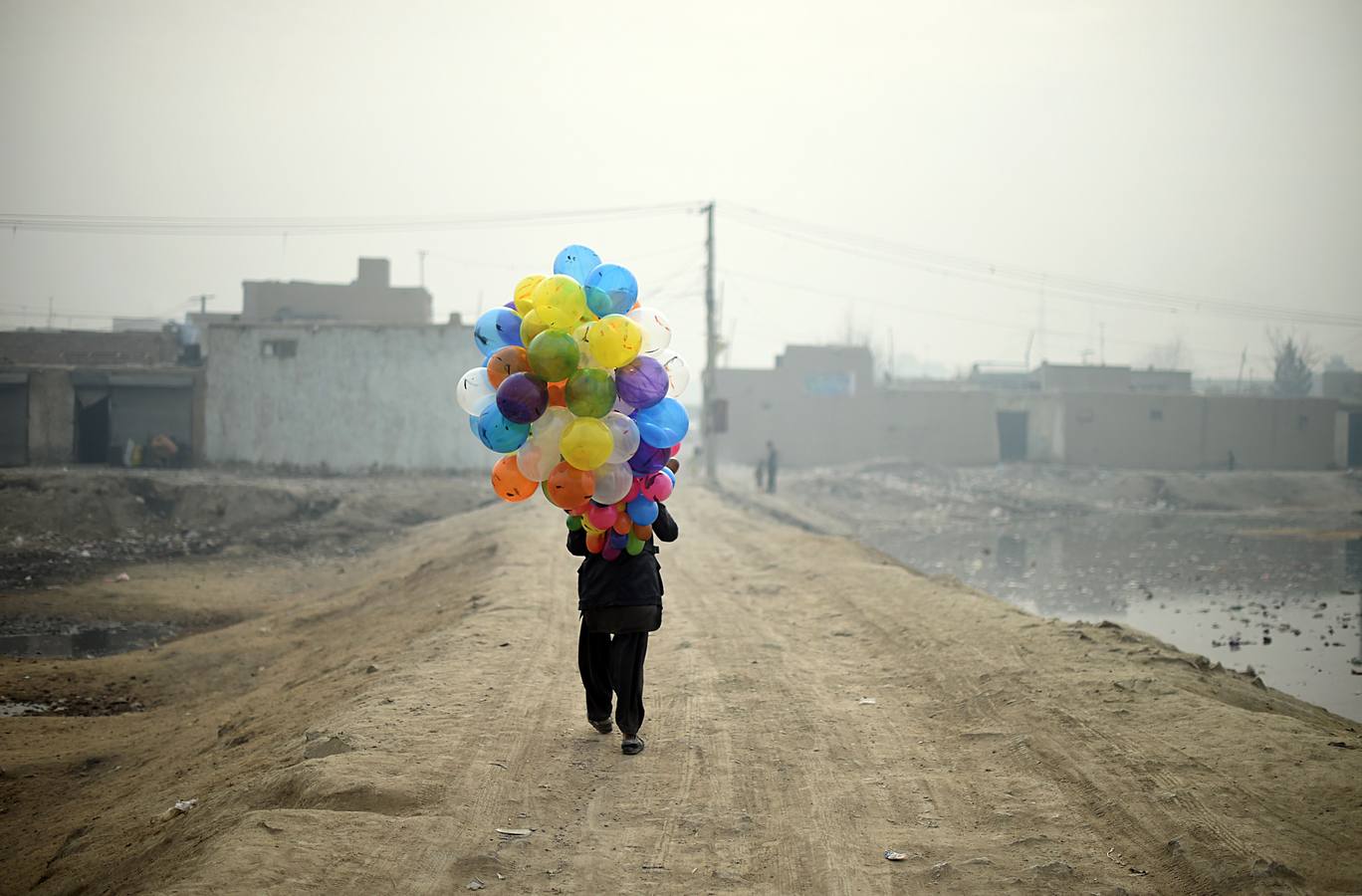 Vendedor de globos afgano Arash, espera a los clientes a medida que camina por un barrio en Kabul.