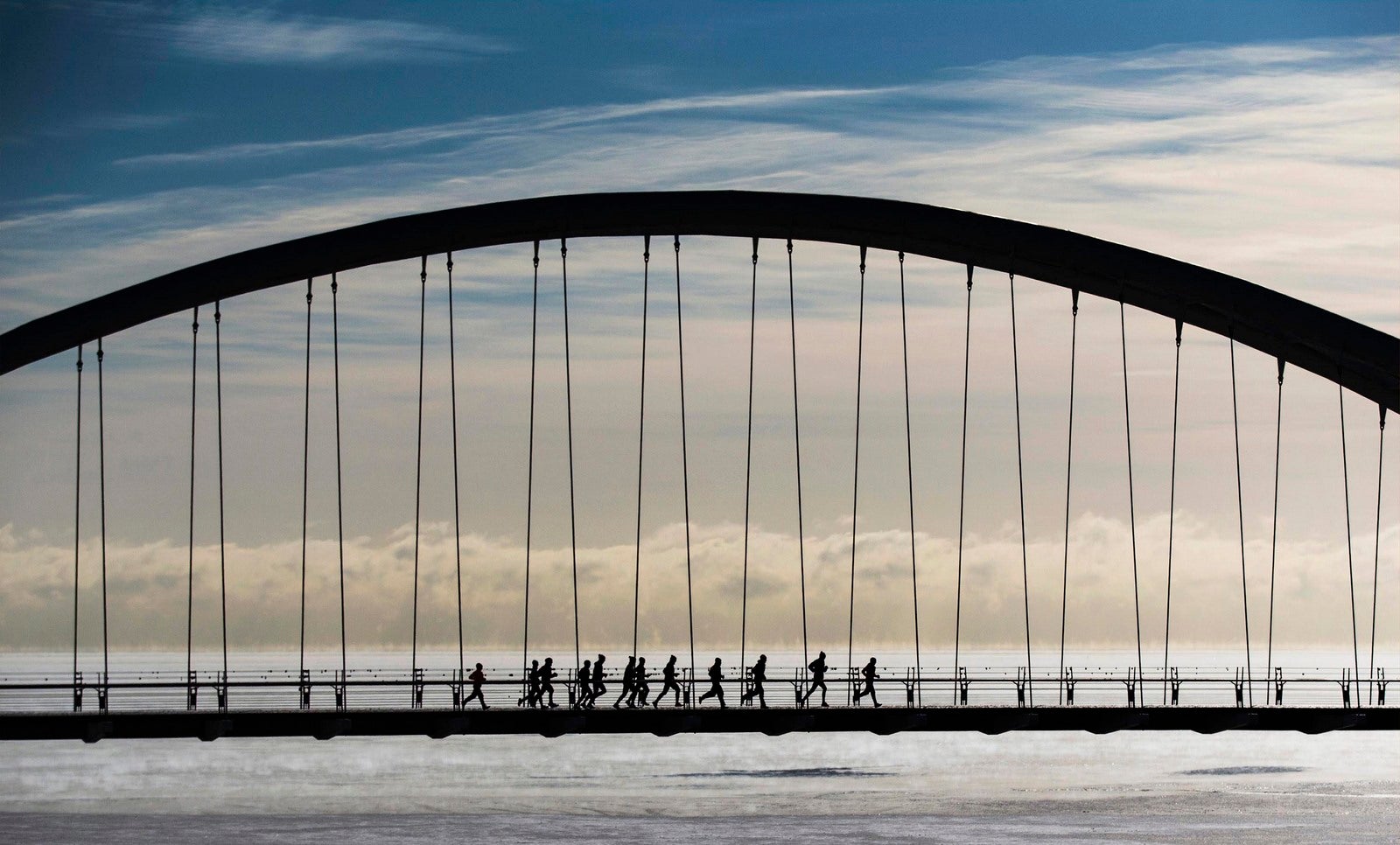 Un grupo de corredores corren a través del puente del arco de la Bahía de Humber en temperaturas de frío extremo en Toronto.