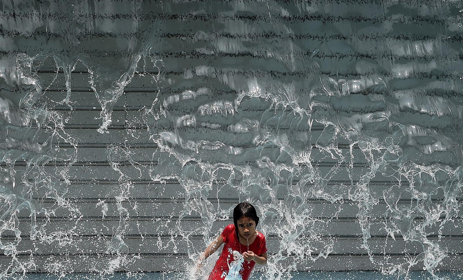 Una niña juega en una cascada artificial en un día caluroso en Kuala Lumpur.