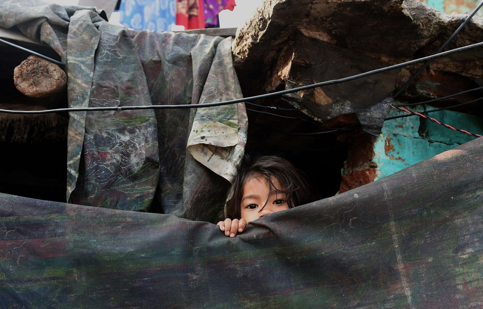 Una joven india se asoma desde su chabola en un barrio pobre de Nueva Delhi.