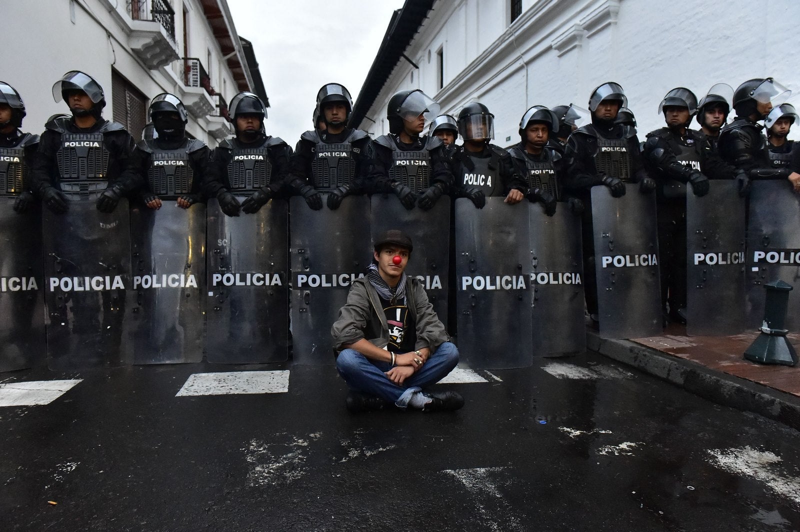 Un joven se sienta delante de una fila de policías antidisturbios durante la manifestacion opositora al presidente ecuatoriano Rafael Correa.
