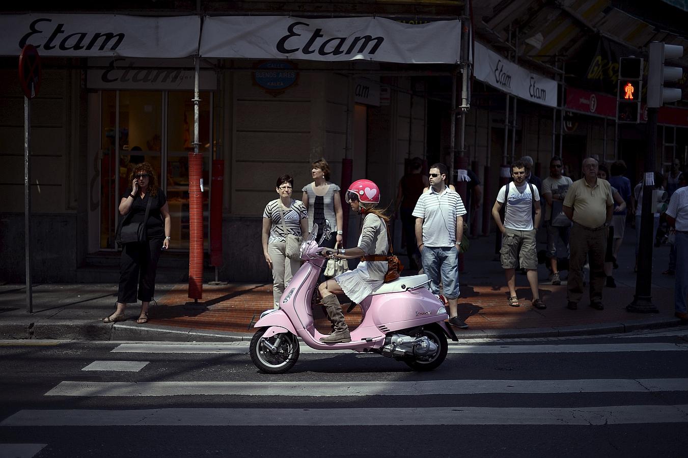 Una niña monta una Vespa por el centro de Bilbao.